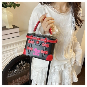 Detail of a vintage box-shaped crossbody bag featuring red trim and pink bunny pattern