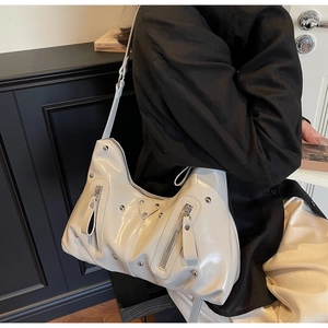 Détail du sac hobo en cuir verni crème avec plaque triangulaire et rivets argentés brillants