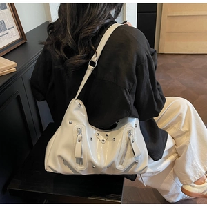 Détail du sac à bandoulière en cuir verni blanc avec rivets et fermoirs argentés