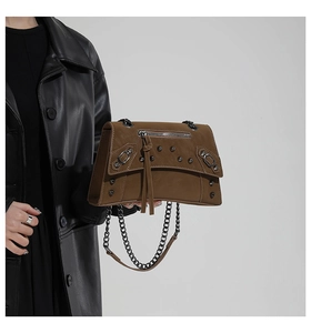 Detail view of brown matte leather bag featuring silver metal studs and long tassels