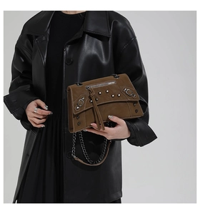 Close-up of vintage dark brown leather crossbody bag with silver studs and chain strap