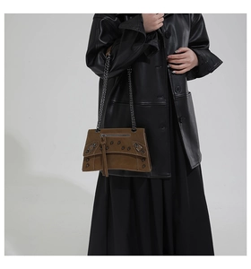 Detail of vintage brown crossbody bag with studs, metal chains and long tassels