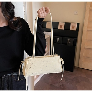 Detail of cream baguette bag with silver star patterns and bow tassel shoulder straps