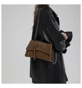 Detail of vintage brown oil wax leather crossbody bag with metal rivets and tassels