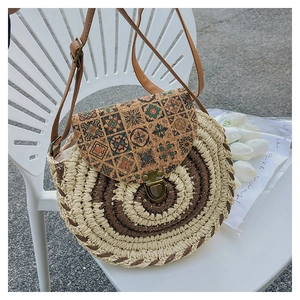 Dettaglio borsa a tracolla rotonda in paglia con patta in sughero etnico e chiusura vintage