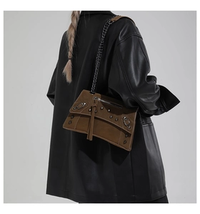 Detail showing vintage brown crossbody bag with silver studs and tassel worn by model
