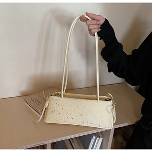 Detail of cream baguette bag featuring silver star prints and delicate side drawstrings