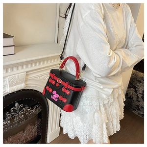 Detail of contrast color crossbody bag featuring black leather and red top handle