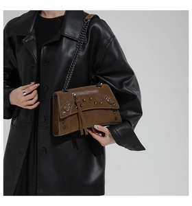 Close-up of dark brown leather crossbody bag with metal rivets and chain strap