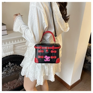 Close-up of a small black and red box bag with pink bunny pattern and metal snap closure