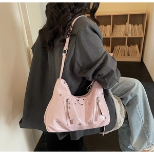 Détail du sac à bandoulière en cuir verni rose brillant avec clous et fermetures éclair argentés