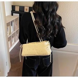 Detail of light yellow baguette bag with star patterns and side bow ribbon
