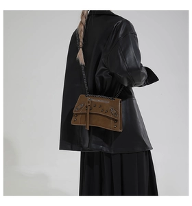 Detail of dark brown leather crossbody bag with metal rivets and long fringe tassels