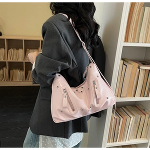 Détail du sac hobo rose en similicuir avec rivets argentés et fermetures éclair décoratives