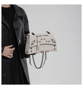 Detail of beige rivet motorcycle bag featuring silver chains and long leather tassels