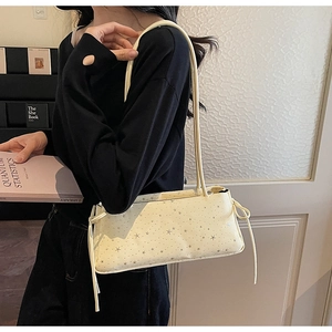Close-up of cream rectangle bag featuring silver star patterns and drawstring details