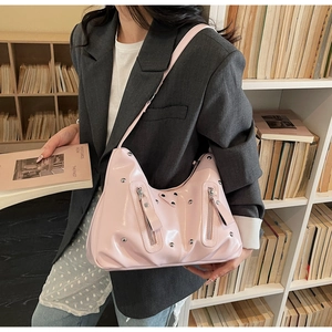 Détail du sac bandoulière en cuir verni rose avec rivets argentés et poches zippées