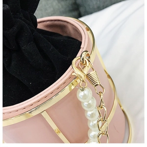 Dettaglio borsa a secchiello in pelle rosa con cornice dorata e catena di perle