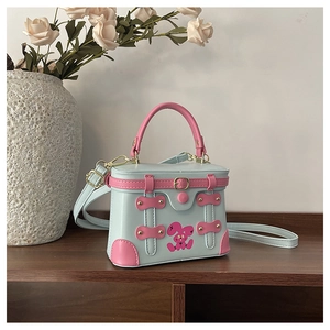 Detailed view of mint green box bag with pink rabbit motif and golden hardware