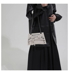 Detail of off-white rivet chain bag on model with punk hardware and matte texture