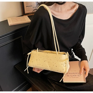 Detailed view of beige baguette bag with star patterns and drawstring bow accents