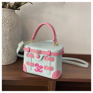 Detail of mint green box bag featuring pink rabbit pattern and gold hardware accents