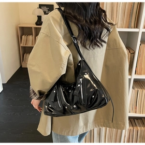 Détail du sac hobo en cuir verni noir brillant avec fermetures éclair et rivets argentés