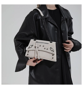 Close-up of beige rivet chain bag with punk metallic studs and decorative zippers