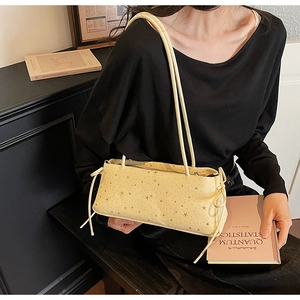 Detail of pale yellow shoulder bag with star pattern and drawstring bow on side