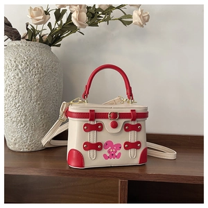 Detail of box handbag featuring red leather straps and cute cartoon bunny illustration