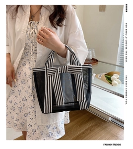 Detail of black mesh tote bag with striped handles and decorative bow in a sunny interior