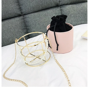 Dettaglio borsa a secchiello a gabbia dorata con pochette rosa e manico di perle chic