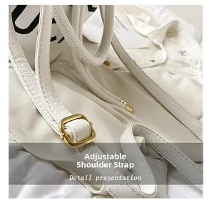 Detail of adjustable shoulder strap with gold buckle on white litchi grain leather bag