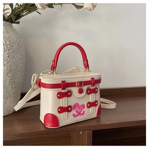 Detail of a white and red box handbag featuring a cute pink rabbit and golden metal clasp