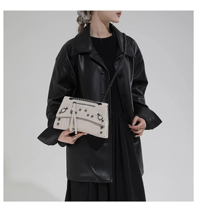 Detail view of retro motorcycle crossbody bag with metal rivets and black chain strap