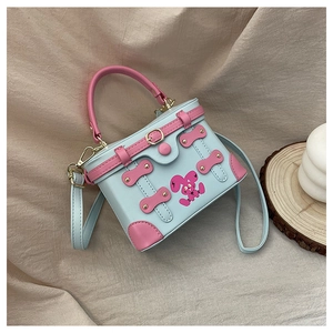 Close-up of a blue box bag with pink handles, rabbit print, and metal rivet details