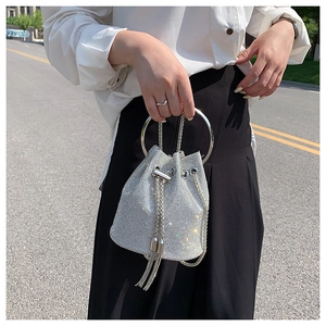 Close-up of sparkling silver rhinestone bucket bag with round metal handle and chain