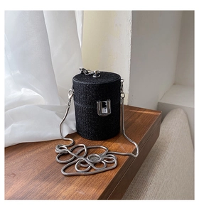Macro shot of black glitter mini cylinder bag with silver chain on wood surface