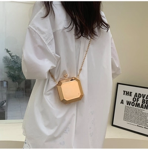 Detail of a geometric gold metal box clutch with chunky bead chain shown as a crossbody
