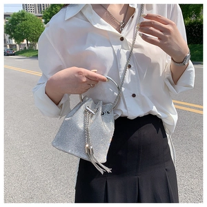 Close-up of sparkling silver rhinestone bucket bag with drawstring and tassel details