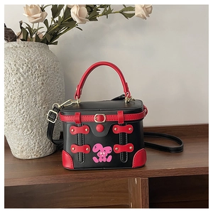 Detail view of retro box handbag with red and black leather contrast and gold hardware