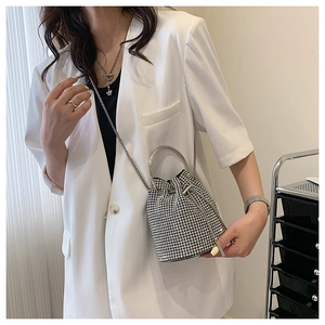 Detail view of silver rhinestone bucket bag with metal handle and chain shoulder strap