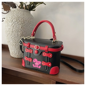 Detail of box-shaped handbag with pink cartoon rabbit and contrast red handles