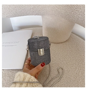 Detailed view of mini cylinder evening bag with dark silver rhinestones and chain strap
