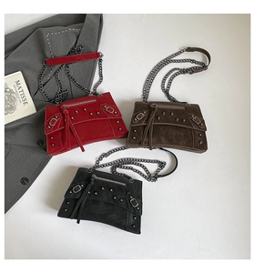 Detail of rivet-studded leather crossbody bags with tassels and metal chain straps