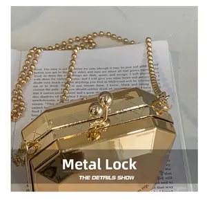 Macro view of golden hexagonal acrylic clutch with metal clasp and bead chain on book