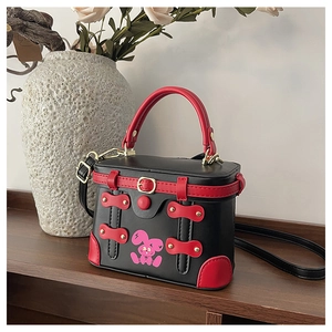 Detail of a retro box-shaped handbag in black and red featuring a cartoon rabbit print