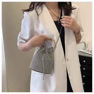 Close-up of sparkling silver rhinestone bucket bag with metal ring handle and chain