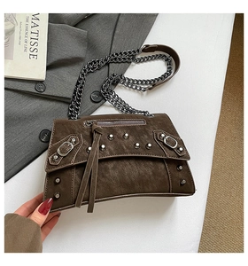 Detail of dark brown rivet chain bag with vintage texture and long tassel accents