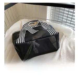 Detail of transparent black mesh tote bag featuring striped woven handles and durable base